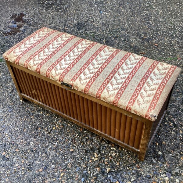 Vintage ottoman with patterned upholstery and wooden slats.