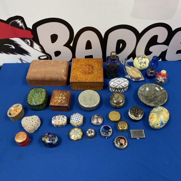 Collection of vintage pill pots and small boxes on a dark surface.