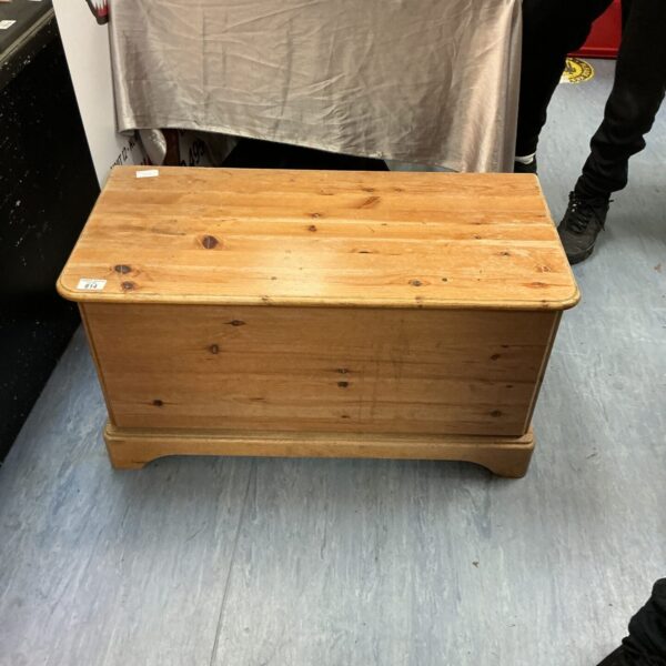 Front view of a vintage pine chest with a lift-top lid.