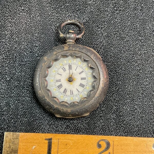 Vintage silver pocket watch with ornate face.