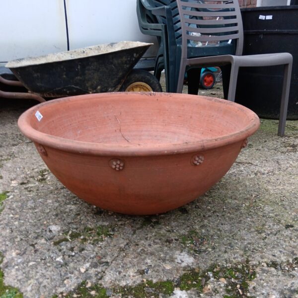Large vintage terracotta planter bowl in a garden setting.