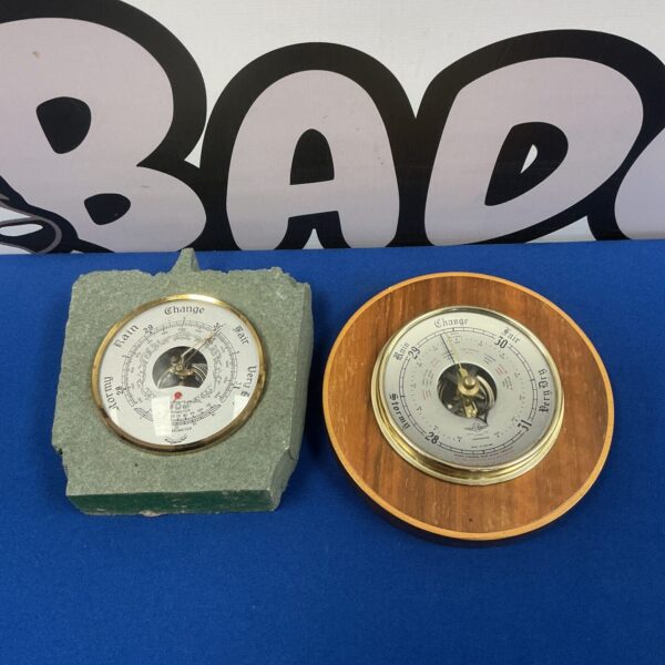 Pair of vintage wall barometers with brass casings and glass fronts.