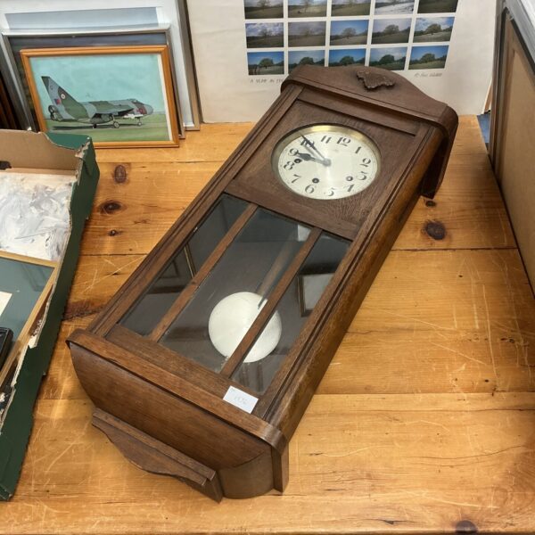 Vintage wooden wall clock with Roman numerals and pendulum.