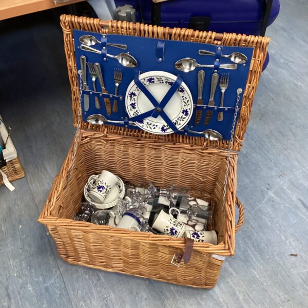 Vintage wicker picnic hamper with porcelain and cutlery inside.
