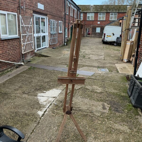 Vintage wooden tripod easel in a courtyard setting.