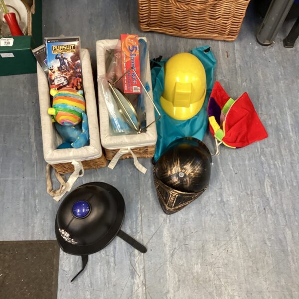 Wicker basket filled with a mixed lot of games and hats.