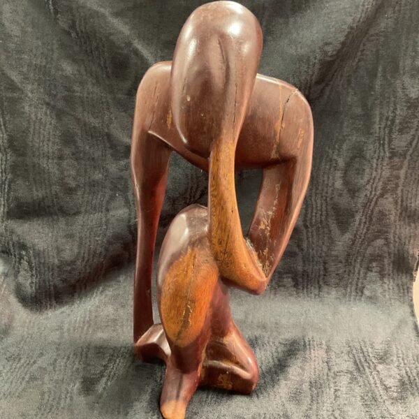 Dark wood sculpture of a thinker figure, modern art.