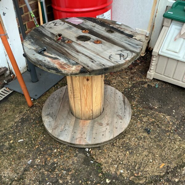 Weathered wooden cable drum, side view, rustic industrial style.