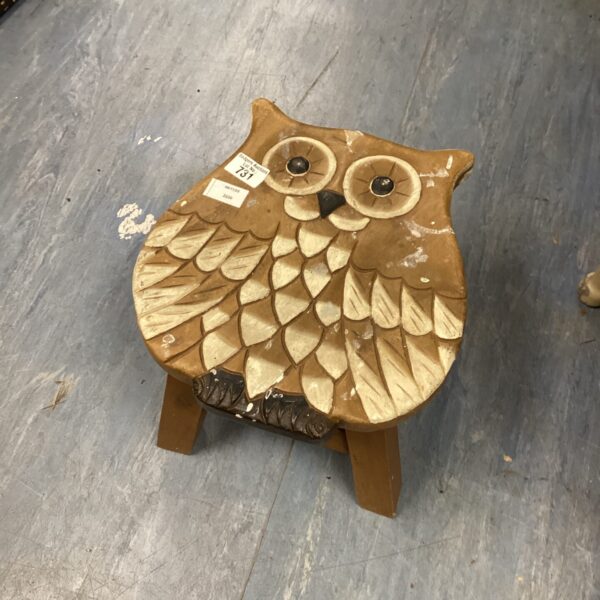 Front view of a hand-carved wooden owl stool.