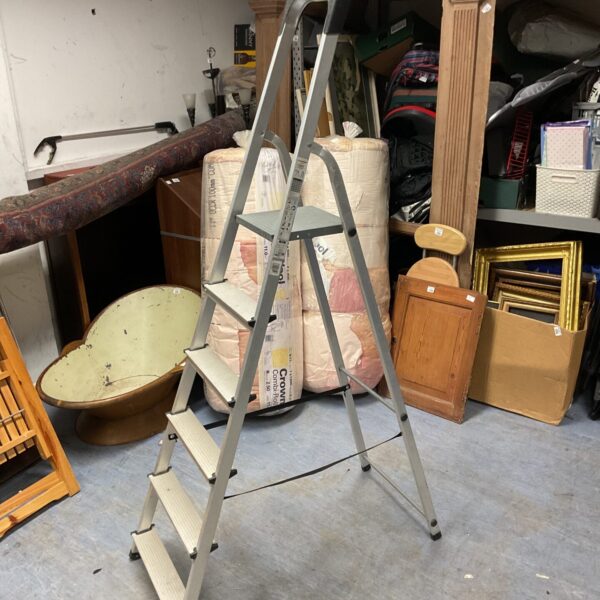 Silver aluminum 5ft step ladder in a cluttered space.
