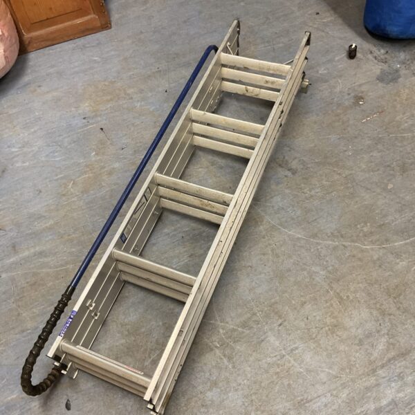 Silver aluminium loft ladder folded and leaning against a wall.