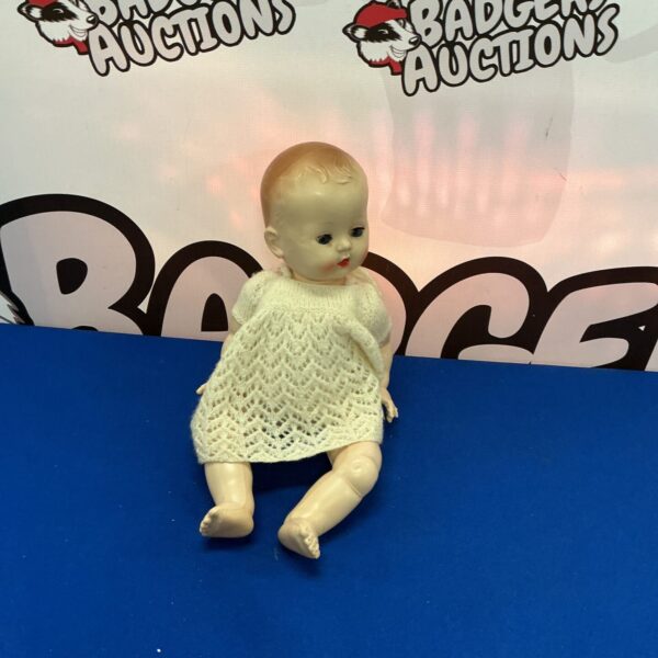 Antique child’s doll in a white lace dress, vintage collectible toy.