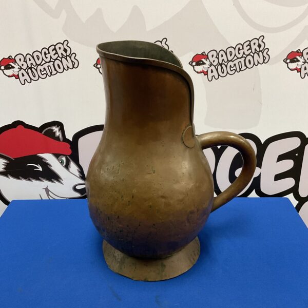 Front view of antique copper brewery jug with patina.