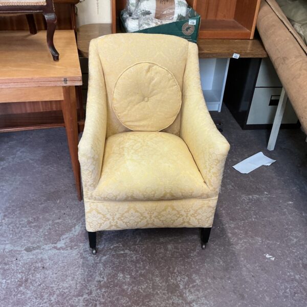 Antique fabric armchair with detailed upholstery and casters.