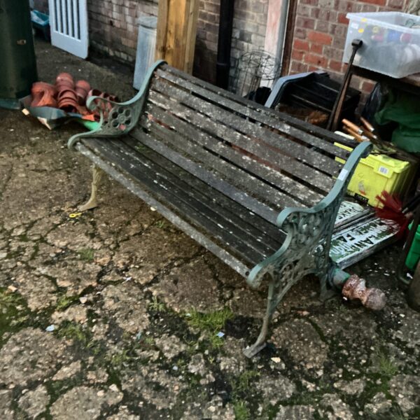 Ornate antique metal garden bench with wooden slats.