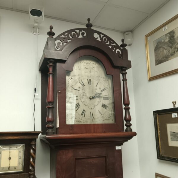 Front view of antique wooden grandfather clock with arched hood.