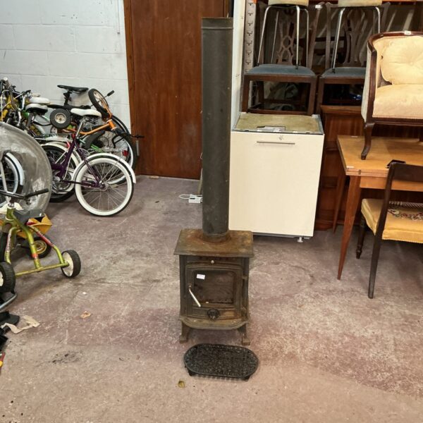 Antique cast iron log burning stove with chimney flue.