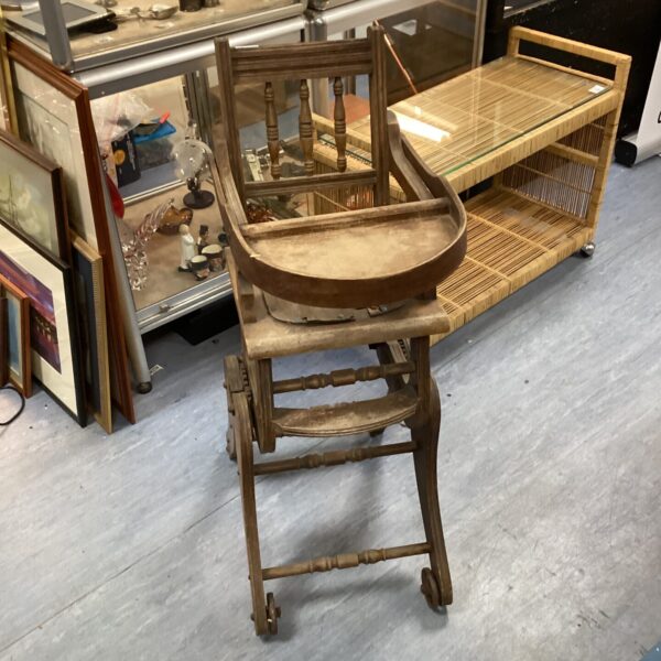 Side view of antique wooden highchair with adjustable height.