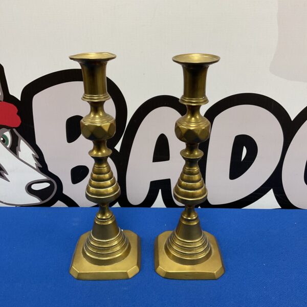 Vintage brass Art Deco candlesticks on a patterned background.
