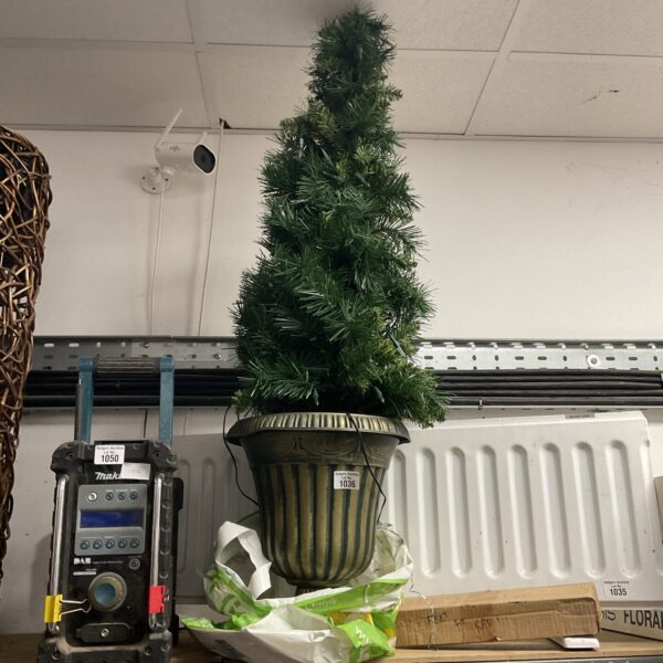Small artificial Christmas tree in a Grecian urn for holiday decor.