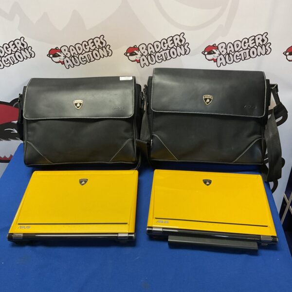 Two Asus Lamborghini laptops with black bags displayed against a backdrop.
