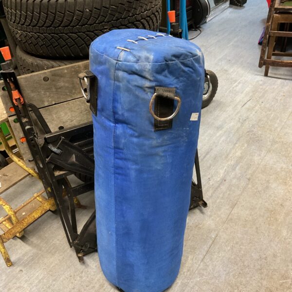 Blue punch bag for boxing and fitness training, showing signs of use.