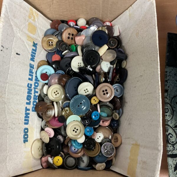 Assorted vintage buttons in a box, ideal for crafting.