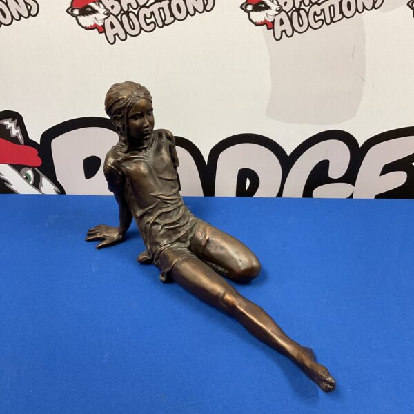 Bronze effect sculpture of a seated young girl.