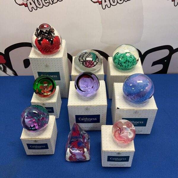 Collection of colourful Caithness glass paperweights on display.