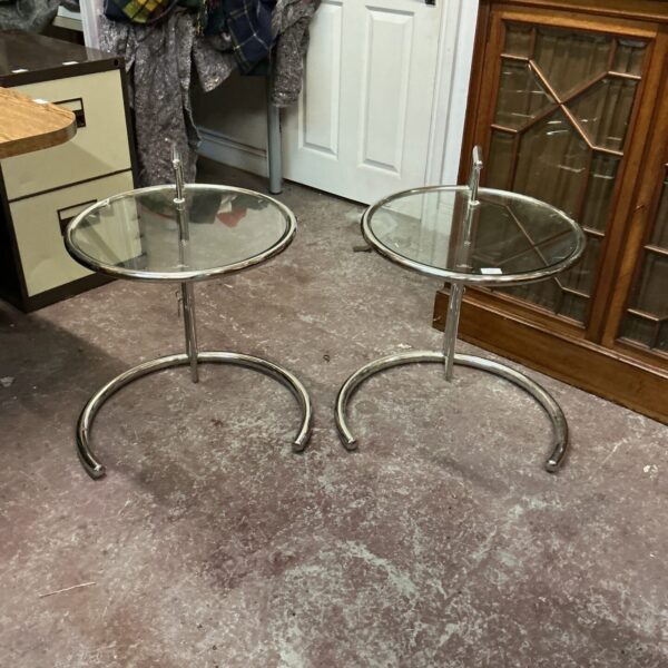 Pair of adjustable chrome and glass coffee tables in a living space.
