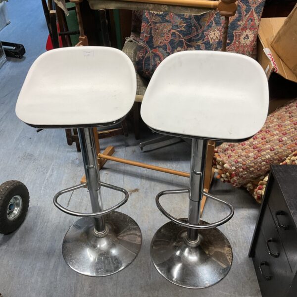 Pair of white and chrome adjustable bar stools for kitchen seating.