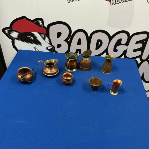 Antique copper jugs and urns collection on a dark surface.