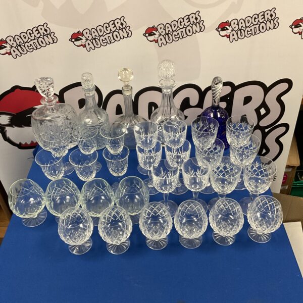 Large lot of vintage crystal decanters and glassware on display.