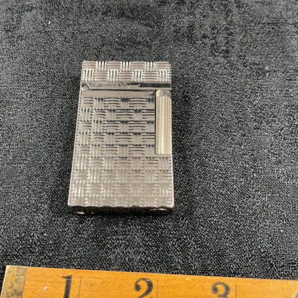 Vintage Dupont lighter with intricate engraved pattern on the front.