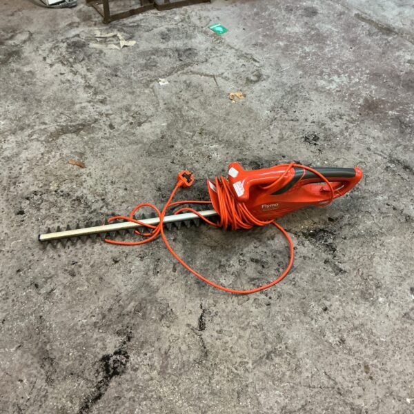Used Flymo electric hedge trimmer with long handle and power cord.