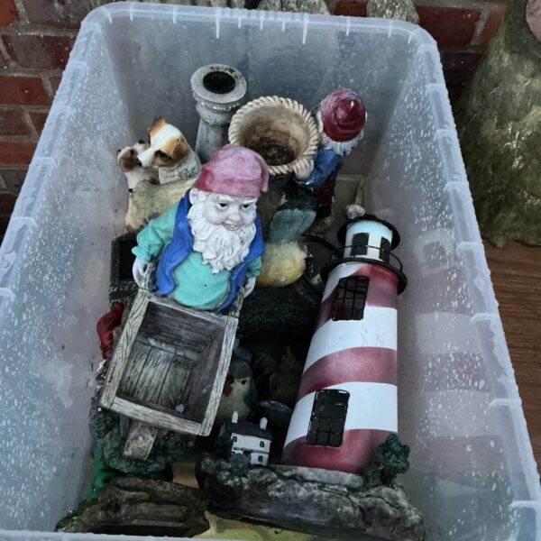 Collection of colourful garden gnomes and a lighthouse ornament.