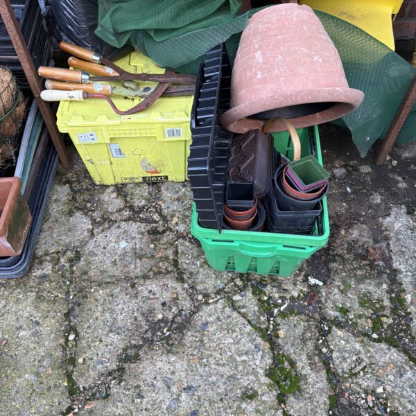 Mixed garden tool lot with terracotta and plastic pots.