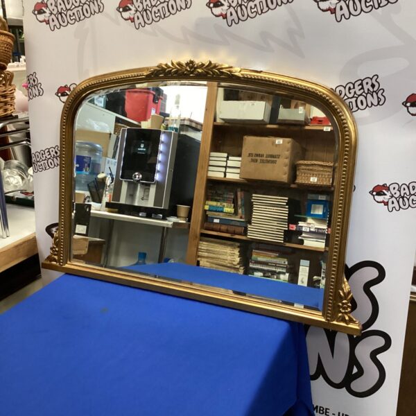 Ornate gilt framed mantle mirror with a vintage aesthetic.