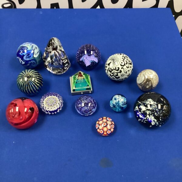 Collection of twelve colourful glass paperweights, including Mdina glass.