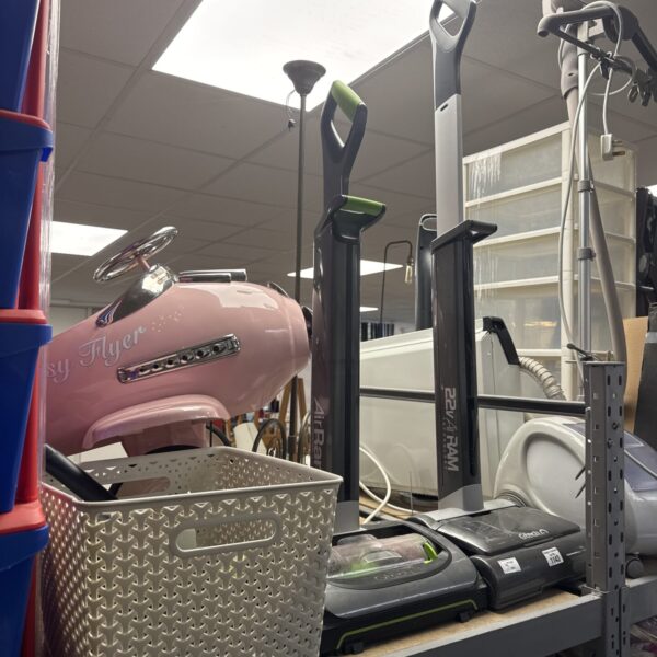 Pink Gtech AirRam cordless vacuum cleaner on a shelf.
