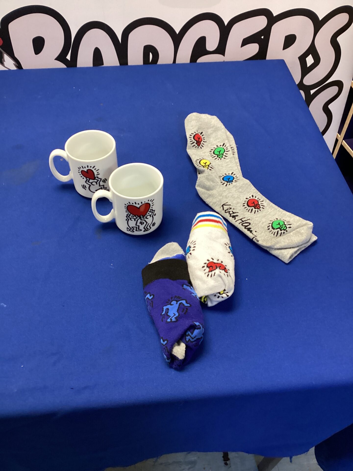 Keith Haring socks and mugs lot, colourful pop art collectibles.