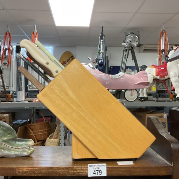 Wooden knife block set with stainless steel kitchen knives displayed on a shelf.