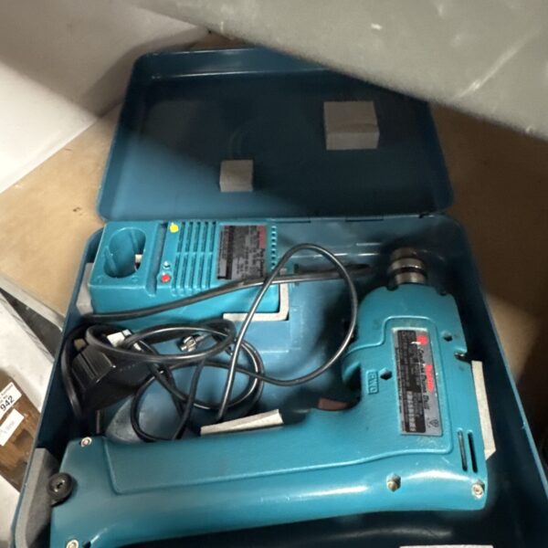 Vintage Makita cordless drill with battery and charger displayed open.