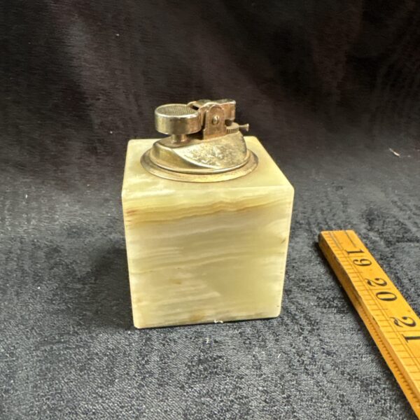 Vintage marble and brass table lighter on a surface.