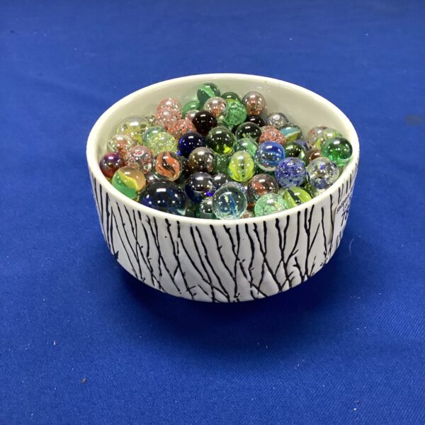 Vintage glass marbles in a white ceramic bowl.
