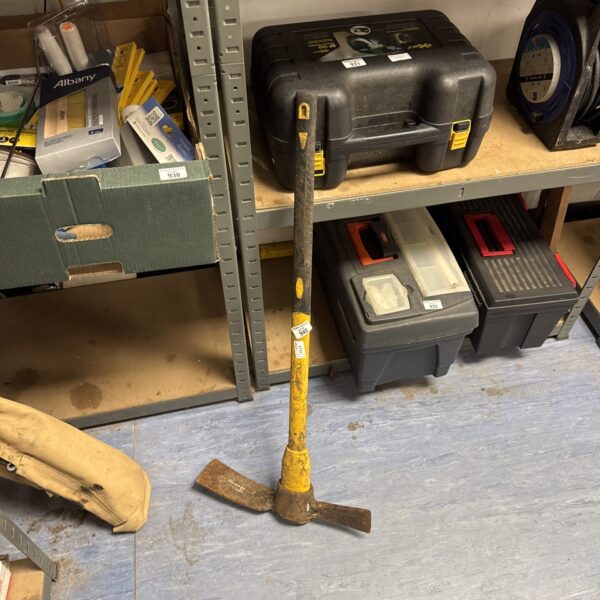 Rusty mattock garden tool with wooden handle.