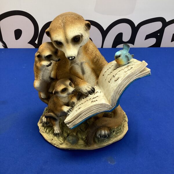 Charming meerkat family garden ornament with open book.