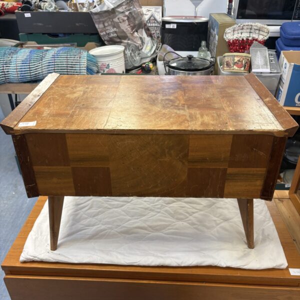 Front view of a vintage mid-century sewing box on a white surface.