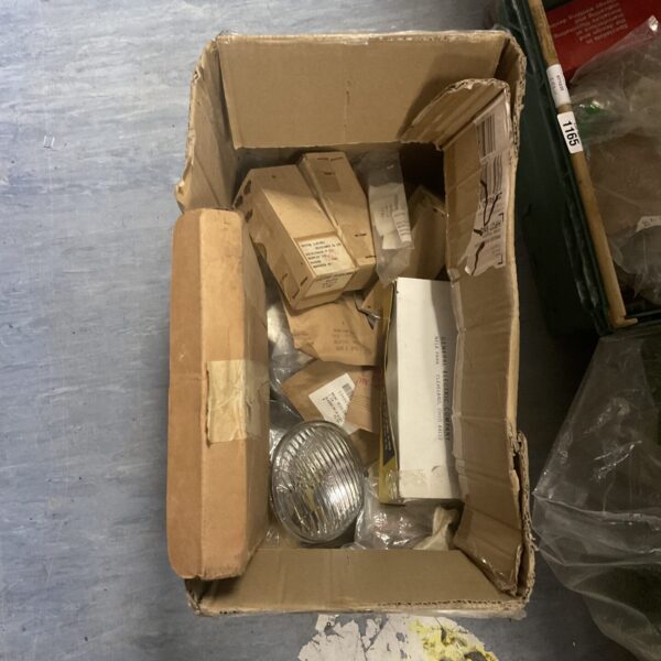 Assorted new old stock military parts in a cardboard box.