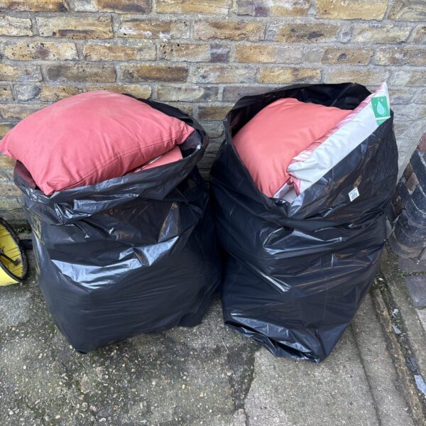 Two bags filled with outdoor cushions for garden seating.